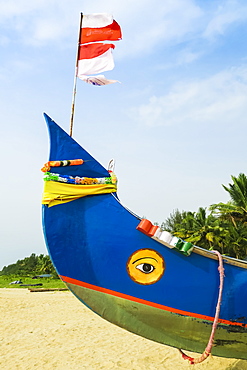 Colourful fishing boat with Indian flag and golden eye motifs on Marari Beach, Mararikulam, Alappuzha (Alleppey), Kerala, India, Asia