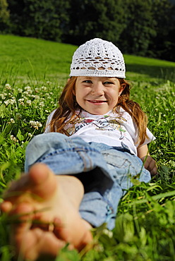 Girl lies barfoot in a meadow