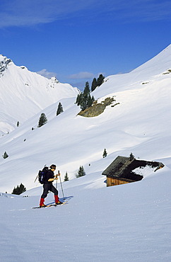 Woman snowshoeing near a mountain hut in the valley Kleinwalser Austria