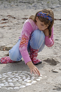 Girl puts with shells mandalas