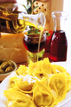 Italian ambiance: drizzling olive oil over an agnolotti dish with parmesan, red wine and olives