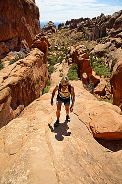 Hiker on a cliff in Devil's Garden, formed by the erosion of sandstone, Arches-Nationalpark, near Moab, Utah, United States