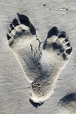 Two footprints in the sand on a beach