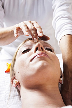 Young woman being treated by a therapist on her head and upper torso