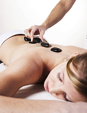 Young woman being treated with hot stones, hot stone massage