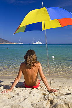 Woman sitting on the beach of Marina di Campo, Island of Elba, Tuscany, Italy, Mediterranean Sea, Europe