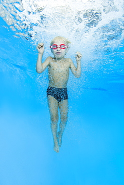 Little boy with swimming goggles, jumping into swimming pool, underwater, Ukraine, Europe