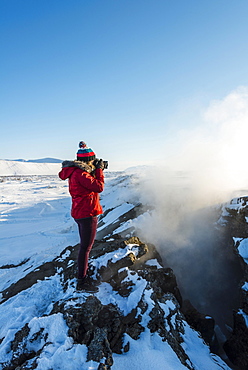 Woman standing at divergent tectonic boundary between North American and Eurasian plates, photographing, Mid-Atlantic Ridge, rift valley, Krafla, Myvatn, Northern Region, Iceland, Europe