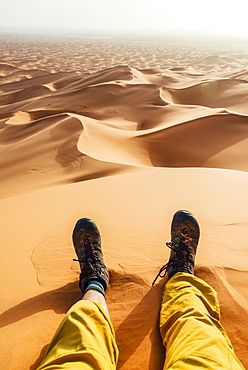 Legs with hiking boots in the sand, sand dune, desert, Erg Chebbi, Merzouga, Sahara, Morocco, Africa