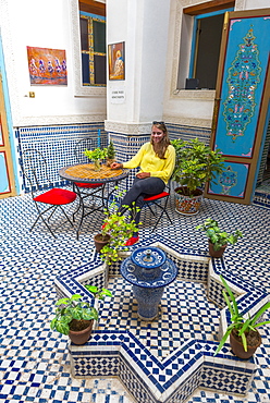 Young woman in a Moroccan courtyard, blue tiles and fountain, Fès-Boulemane, Morocco, Africa