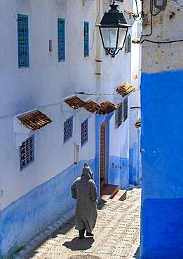 Local in Djellaba, stairs through narrow lane, blue houses, Medina of Chefchaouen, Chaouen, Tanger-Tetouan, Morocco, Africa