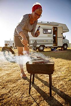 Woman camping, barbecuing in front of her motorhome, Portbail, Normandy, France, Europe