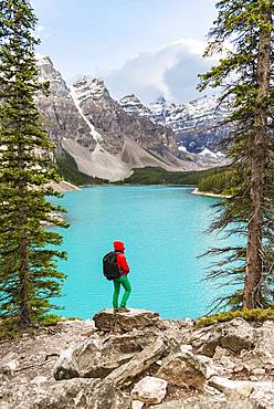 Hiker standing on the shore of a lake, mountain peaks at the back, turquoise glacial lake, Moraine Lake, Valley of the Ten Peaks, Rocky Mountains, Banff National Park, Alberta Province, Canada, North America