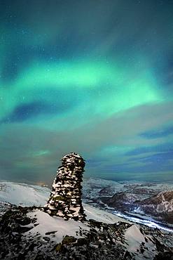 Northern Lights (aurora borealis), with stone figure in cloudy sky on Jamnfjellet, Tromsoe, Norway, Europe