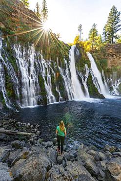 Young woman standing at a waterfall, McArthur-Burney Falls Memorial State Park, California, USA, North America