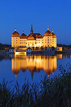 Illuminated Moritzburg Castle at dusk, water reflection in the lake, Saxony, Germany, Europe