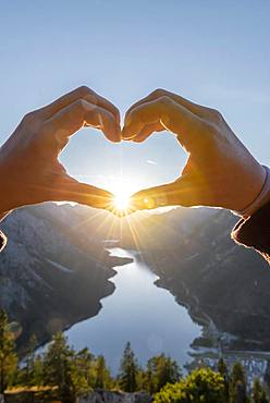 Hand forms a heart in front of alps and mountain lake, sun star, symbol love for nature and hiking, view from Schoenjoechl, Plansee, Tyrol, Austria, Europe