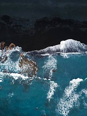 Black volcanic beach with rocks and waves running out from above, black sand, drone shot, Lanzarote, Spain, Europe