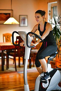 Young woman doing sports at home on an ergometer, Stuttgart, Baden-Wuerttemberg, Germany, Europe