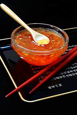 Chilli sauce with spoon in glass bowl and red chopsticks, Germany, Europe