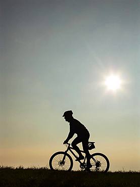 Cyclist on bike tour with mountain bike, silhouette against the light, Salzkammergut, Upper Austria, Austria, Europe