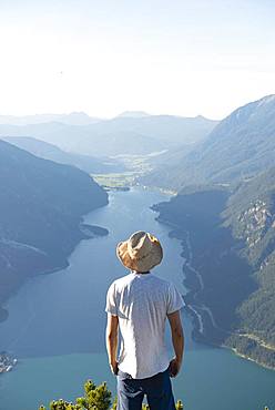 Young man looks over mountain landscape, summit of the Baerenkopf, view of the Achensee, Karwendel, Tyrol, Austria, Europe