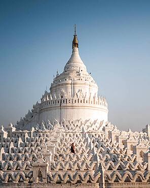 Buddhist monk stands with red umbrella in front of Hsinbyume Pagoda, Mingun, Myanmar, Asia