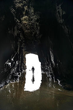 Silhouette of a person in front of cave exit in backlight, cave washed out by the sea, Cathedral Cave, Waipati Beach, The Catlins, Southland, South Island, New Zealand, Oceania