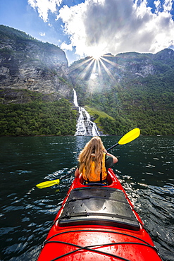 Young woman paddling in a kayak, Freier waterfall, Geirangerfjord, near Geiranger, Norway, Europe