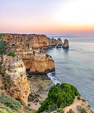 Rugged rocky coast with cliffs of sandstone, rock formations in the sea, Ponta da Piedade, dawn at sunrise, Algarve, Lagos, Portugal, Europe