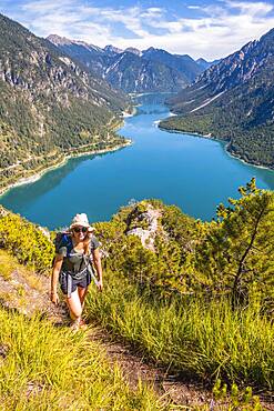 Hiker walking at Plansee, mountains with lake, Ammergau Alps, district Reutte, Tyrol, Austria, Europe