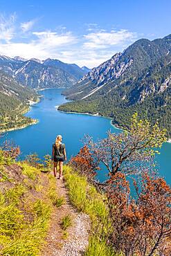 Hiker walking at Plansee, mountains with lake, Ammergau Alps, district Reutte, Tyrol, Austria, Europe