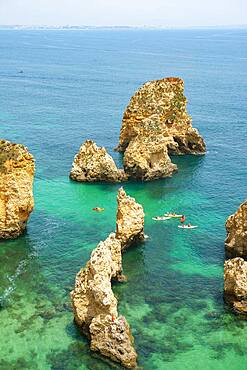 SUPs in the turquoise sea between rock formations, Rugged rocky coast with cliffs of sandstone, Ponta da Piedade, Algarve, Lagos, Portugal, Europe