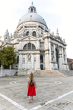 Young woman with red dress in front of church, Basilica di Santa Maria della Salute, Venice, Veneto, Italy, Europe