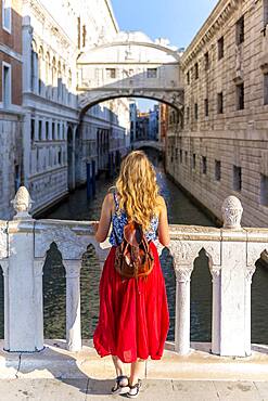 Young woman with red skirt, tourist on a bridge over the Rio di Palazzo, behind Bridge of Sighs, Venice, Veneto, Italy, Europe