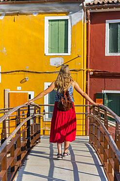 Young woman in front of colorful houses, colorful house facades, Burano Island, Venice, Veneto, Italy, Europe