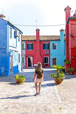 Young woman in front of colorful houses, colorful house facades, Burano Island, Venice, Veneto, Italy, Europe