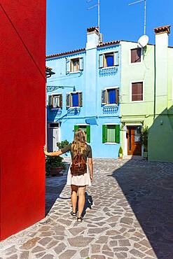 Young woman in front of colorful houses, colorful house facades, Burano Island, Venice, Veneto, Italy, Europe