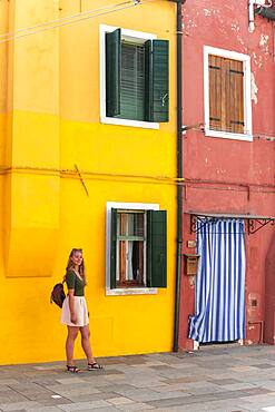 Young woman in front of colorful house, colorful house facades, tourist on Burano island, Venice, Veneto, Italy, Europe