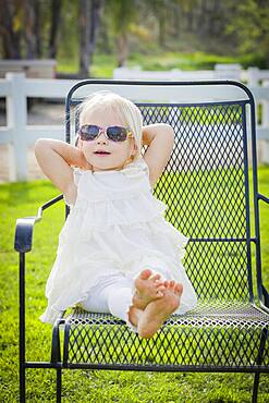 Cute playful baby girl wearing sunglasses outside at the park