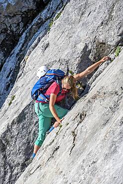 Young woman climbing along a rock face, hiking to the Hochkalter, Berchtesgadener Alpen, Berchtesgadener Land, Upper Bavaria, Bavaria, Germany, Europe