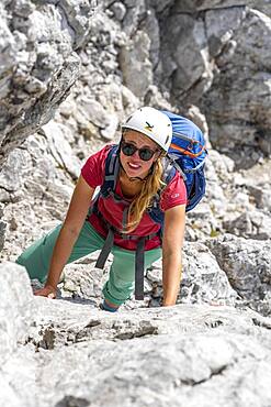 Young female hiker climbing with helmet, rocky mountains and scree, hiking to the Hochkalter, Berchtesgadener Alpen, Berchtesgadener Land, Upper Bavaria, Bavaria, Germany, Europe