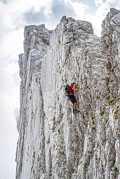 Young man climbing a vertical rock face without a rope, rocky mountains and scree, near Hochkalter, Berchtesgadener Alpen, Berchtesgadener Land, Upper Bavaria, Bavaria, Germany, Europe