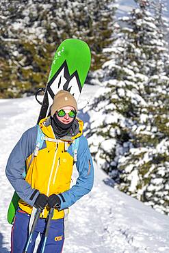 Young man with snowboard on his back, ski tourer on tour to Teufelstaettkopf, Ammergau Alps, Unterammergau, Bavaria, Germany, Europe