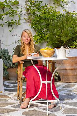 Young woman holding cup, breakfast on holiday outside, Greece, Europe