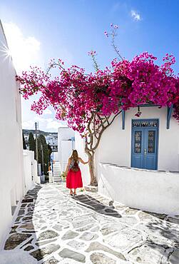 White-blue houses with blooming purple Bougainvillea (Bougainvillea), Young woman with red dress in the old town of Lefkes, Paros, Cyclades, Greece, Europe