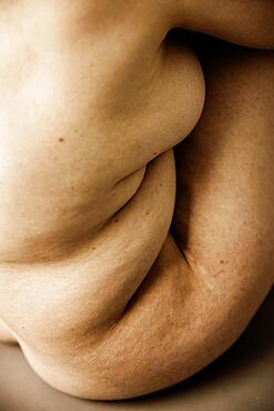 Wrinkled body of a seated naked, fat, older woman, studio shot, Germany, Europe