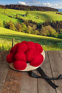Black Forest Bollen hat on wooden table in front of hilly landscape, Black Forest, Baden-Wuerttemberg, Composing, Germany, Europe