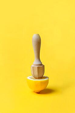 Lemon and lemon squeezer against a yellow background