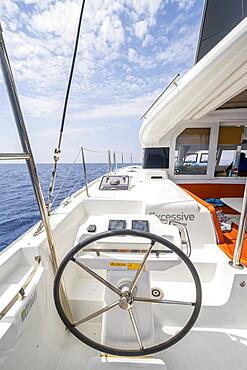 Steering wheel in the cockpit on the deck of a sailing catamaran, sailing trip, Dodecanese, Greece, Europe